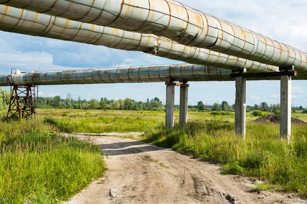 Піднята ділянка трубопроводів над ґрунтовою дорогою — стокове фото