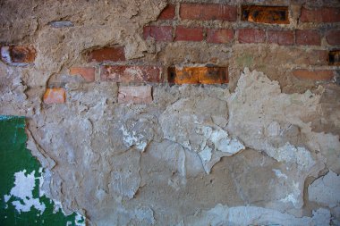 Hasarlı alçılı eski tuğla duvar.