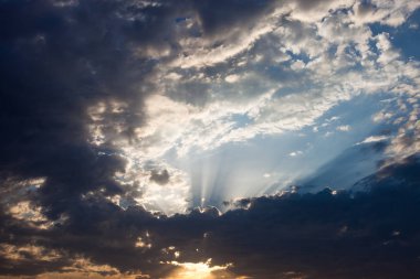Bulutlar bulutların arkasından güneş ışınları yayılıyor.