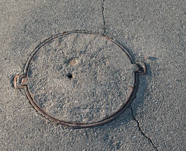 Alcantarilla con la cubierta pavimentada con asfalto — Foto de Stock