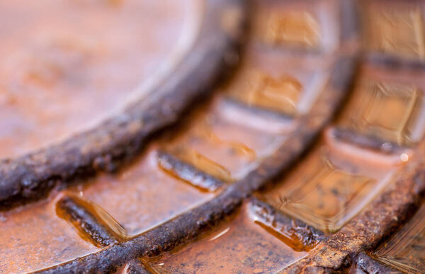 Close up of the rusty metal manhole cover with water