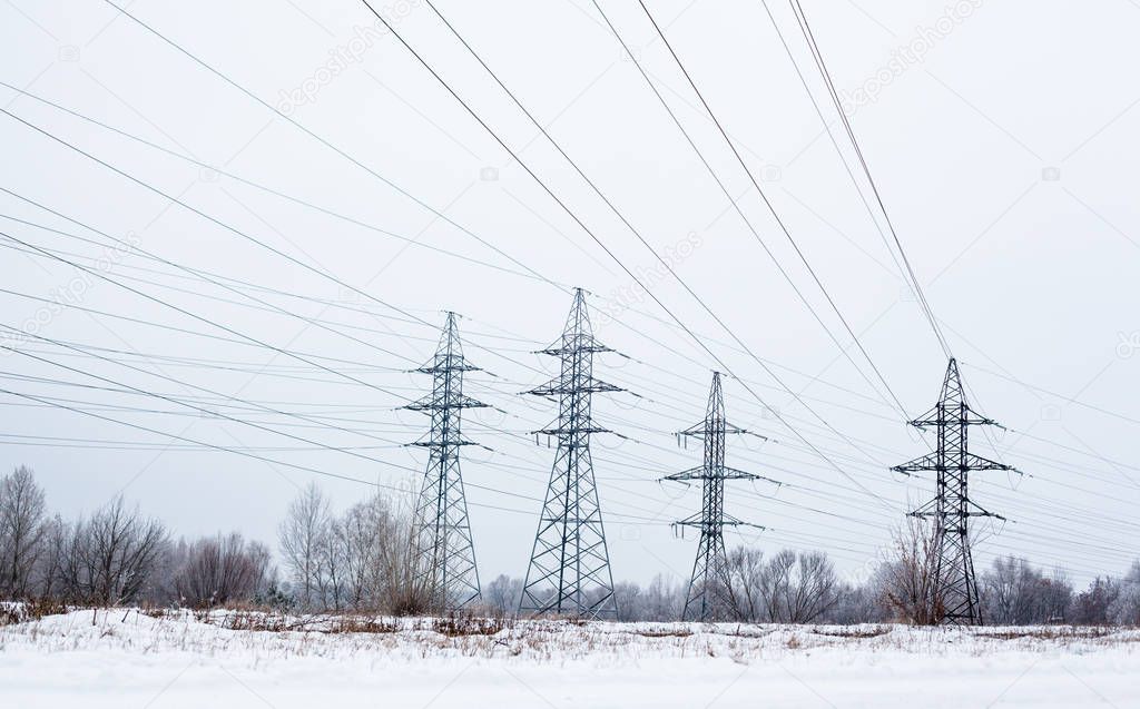 System of electricity pylons and power lines out-of-town in the winter day.