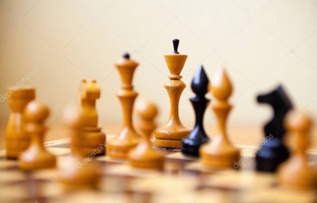 Black and white wooden chess pieces on the chessboard. Chess game.
