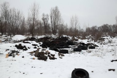 Eski kullanılmış lastik kılıfları ve kışın çöplükteki karda bulunan diğer çöpler. Çevre kirliliği.