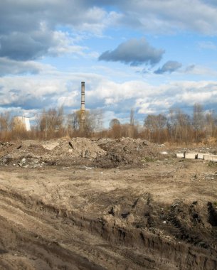 Arka planda çöplük ve endüstriyel fabrika var. Çevre kirliliği. Tekerlek izleri yerde. Sanayi manzarası. 