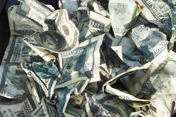 Pile of crumpled one hundred-dollar bills on the ground.