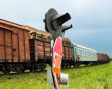Yük treni trafik ışıkları ve tabelalarla demiryolu geçidini geçiyor.