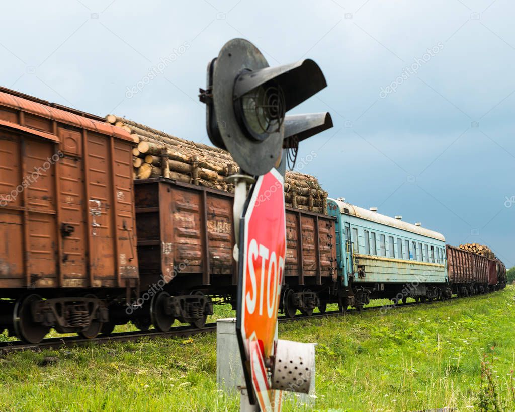 Freight train passing the railroad crossing with traffic lights and signs