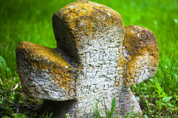 Old moss-grown stone cross with engraved Old Church Slavonic inscriptions. Kyiv, Ukraine. Close up.
