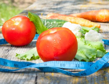 Farklı sebzeler ve mezura. Domates, salatalık, havuç, karnabahar ve marul. Sağlıklı beslenme. Vitamin zindeliği diyeti.