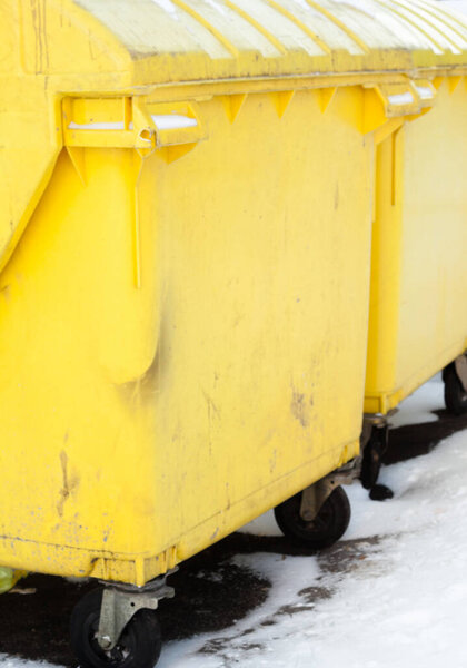 Yellow plastic waste containers (dustbins, garbage cans, trash cans) in winter.