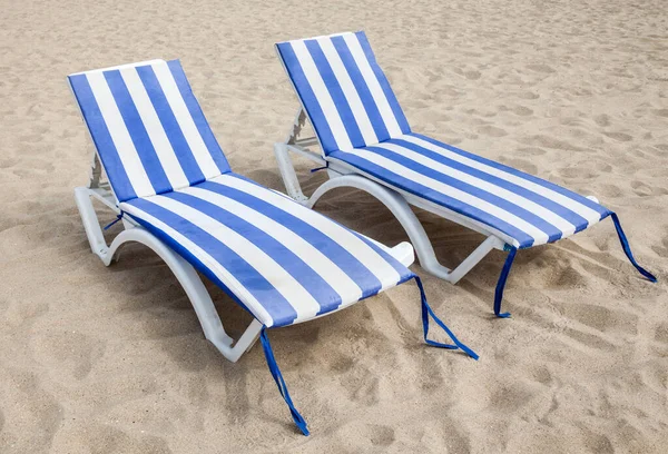 Empty deck chairs on the sand on the beach.