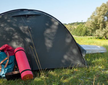 Nehrin yanında çadır ve pedler yuvarlanmış. Kamp alanı.