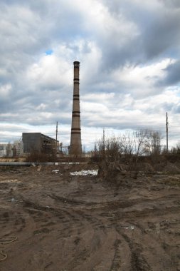 Arka planda çöplük ve endüstriyel fabrika var. Çevre kirliliği. Tekerlek izleri yerde. Sanayi manzarası. 