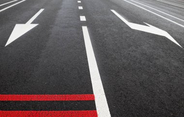 Beyaz yol çizgileri ve yolda kırmızı gürültü şeritleri. Yoldaki oklar. 