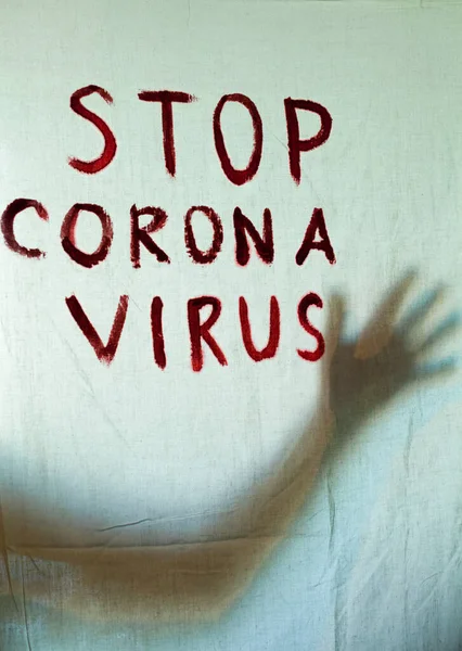 Stop Corona Virus inscription on a white sheet. Silhouette of the hand behind the sheet. Coronavirus (Covid-19) disease outbreak. Quarantine.