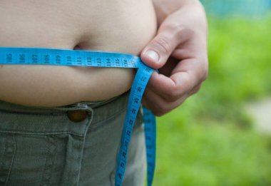 Koca göbekli bir kadın. Bel ölçüsünü şeritle ölçmek.