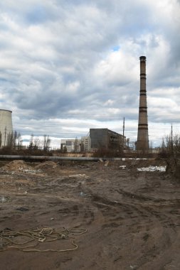 Arka planda çöplük ve endüstriyel fabrika var. Çevre kirliliği. Tekerlek izleri yerde. Sanayi manzarası. 