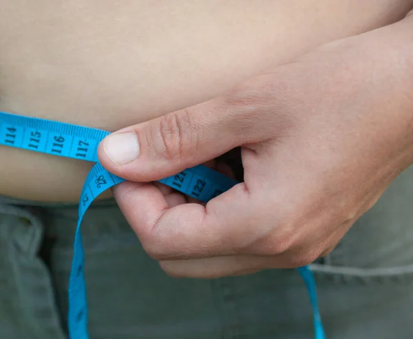 Woman with big belly. Measuring the waist with tape measure.