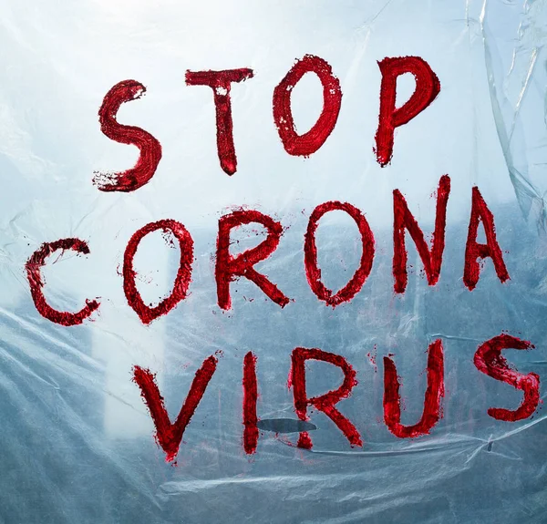 Stop Corona Virus inscription on a polythene surface hanging on a window. Coronavirus (Covid-19) disease outbreak.