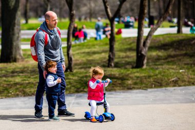 Montreal, Canada - May 5, 2019: Father playing with his babies by the lake of castor in Mont-Royal of Montreal