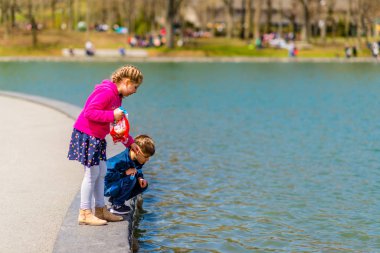 Montreal, Canada - May 12, 2019: Two kids watching fish by the lake of castor in Mont-Royal of Montreal