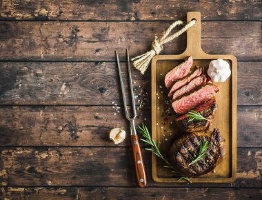 Izgara mermer et steak fileto Mignon, baharat, çatal, ahşap kesme tahtası dilimlenmiş. Metin için yer. Sulu et biftek. Sığır eti biftek ızgara/kızarmış. Üstten Görünüm. Kavrulmuş et biftek. Yakın çekim. Rustik