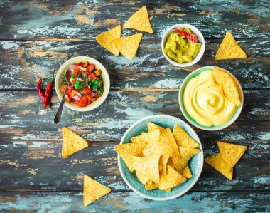 Guacamole, peynir, salsa dips ile Meksika tortilla cips. Cips ve çeşitli dips. Meksika partisi yemek, meze. Üstten Görünüm. Tortilla cips, soslar, acı biber, avokado, rustik ahşap arka plan