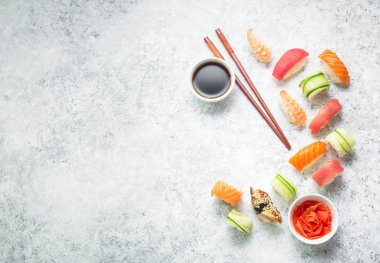 Çeşitli suşi beyaz beton zemin üzerine ayarla. Metin için yer. Japon Suşi rulo, soya sosu, zencefil, yemek çubukları. Üstten görünüm. Suşi nigiri. Japon yemeği/Öğle Yemeği. Gıda çerçeve. Farklı suşi karışık