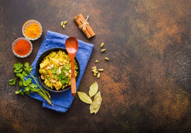 Biryani pirinç, geleneksel Hint yemeği. Baharatlı biryani pirinç, tavuk, fındık. Hint Pilav kasesi, baharatlar, bitkiler, rustik taş arka plan. Üstten görünüm. Metin için yer. Asya tarzı biryani pirinç. Hint yemeği
