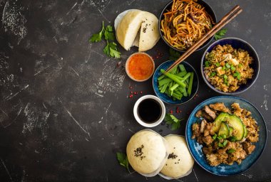 Asya çeşitli gıda kümesi, karanlık rustik taş arka plan. Çin yemekleri. Çin kizartma noodles, et, dim sum, atıştırmalıklar, Asya pirinç Çince buns atmak. Metin için yer. Üstten görünüm. Asya tarzı 