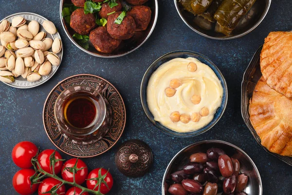 伝統的な中東の盛り合わせメゼ フムス サモサ オリーブ ピスタチオ ファラフェル 青い素朴な背景の上から見た紅茶とドルマ 昼食や夕食のためのアラブ料理 中東料理 — ストック写真