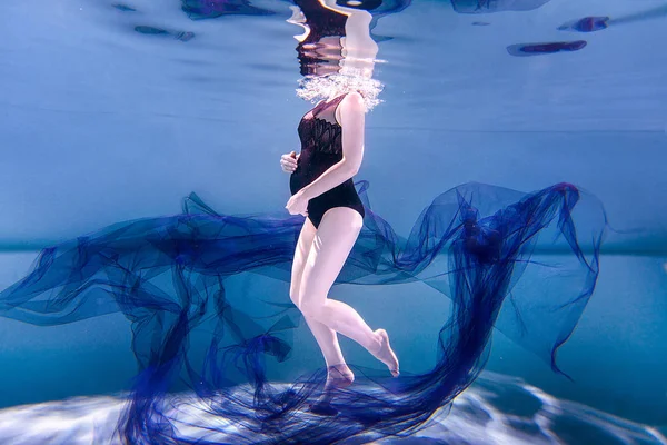 pregnant woman in swimsuit with fabric under water
