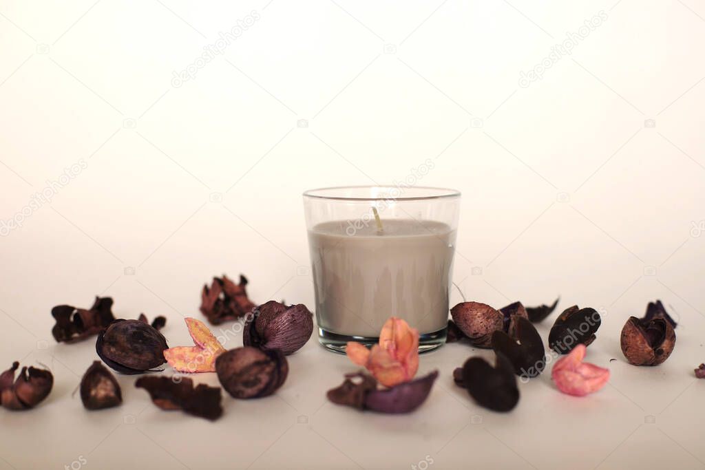 Candle in a glass around flower petals