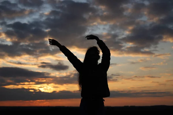 一个在日落时举起双手的年轻女孩的轮廓 感觉快乐并举起一只手 日落时间 — 图库照片