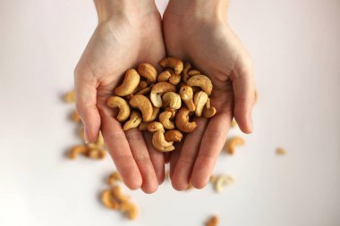 Kız beyaz bir izolasyonda fındıkları elinde tutuyor. Beyaz arka planda bir kızın avuçlarında fındıklar.