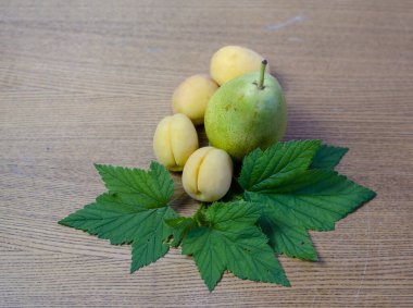 Hala şeftali armudu ve yeşil frenk üzümü yaprağı var masada.