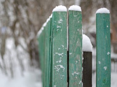 Bir şehir bahçesinin alçak çitleri, bir kar tabakasının altında.