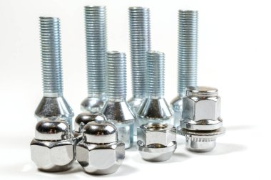 Beyaz bir arka planda. Araba tekerlekleri için yeni parlak vidalar ve vidalar.