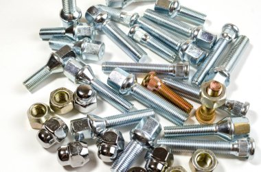 Beyaz arka planda yakın plan araba tekerlekleri için bir sürü yeni somun ve cıvata.