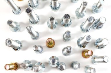 Beyaz bir arka planda, yeni parlak fındıklar ve araba üst görüntüsünün cıvataları.