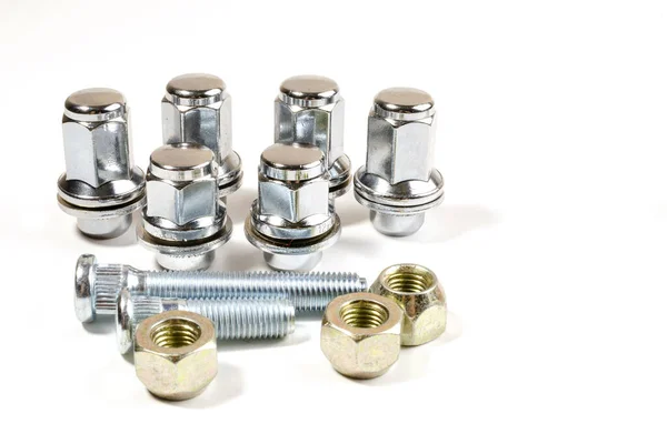 Beyaz arka planda yakın plan araba tekerlekleri için bir sürü yeni somun ve cıvata.