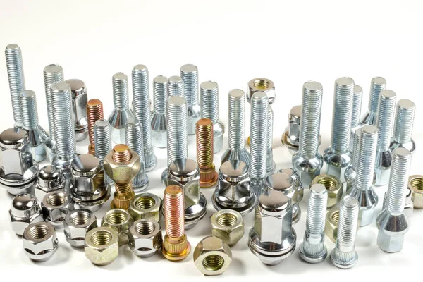 Beyaz bir arka planda, yeni parlak fındıklar ve araba üst görüntüsünün cıvataları.