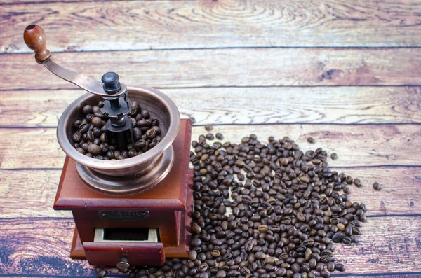テーブルの上には焙煎したコーヒー豆と木製のケースのある銅製のコーヒーグラインダー — ストック写真