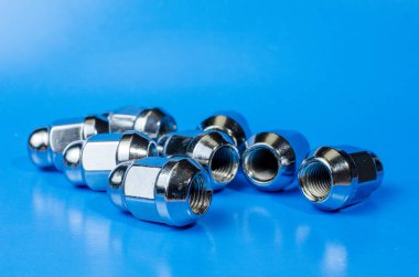 Mavi arka plandaki arabanın direksiyonunu sağlamlaştırmak için parlak metalik fındıklar.