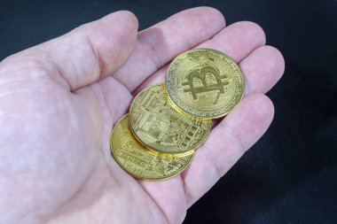 Bir adamın elinde birkaç altın sikke Bitcoin