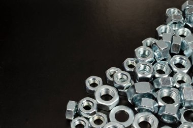 İnşaatta kullanılmak üzere siyah zemin üzerindeki metal fındıklar.