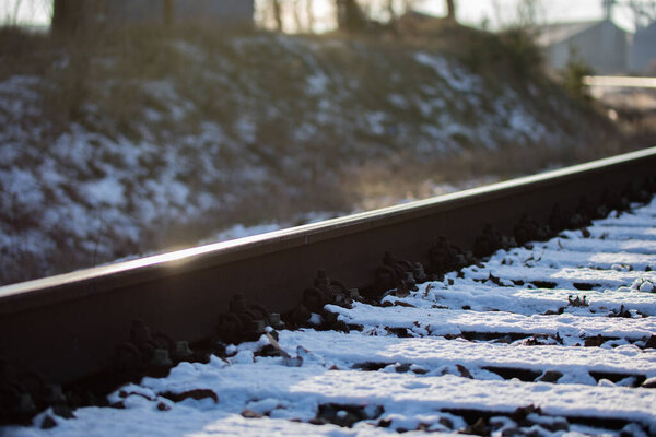 Солнце, отражающееся на железнодорожных рельсах зимой на снежном фоне
