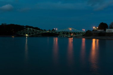Geceleri eski yeşil metal köprünün manzarasına uzun süre maruz kalmışlar. Yumuşak mavi su.