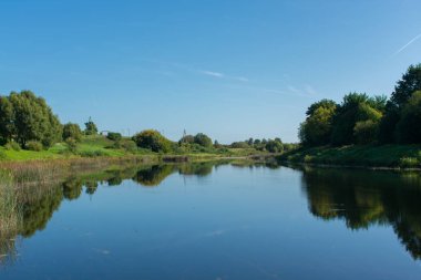Göl manzarası, yeşil adalar ve orman arka planı.